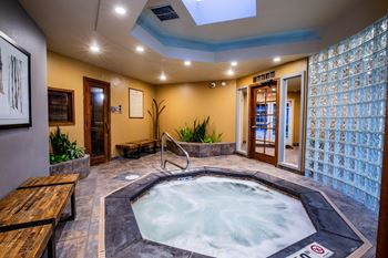 A hot tub in a room with a glass block wall.
